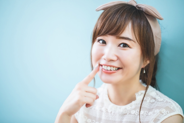 口元を指さす女性

