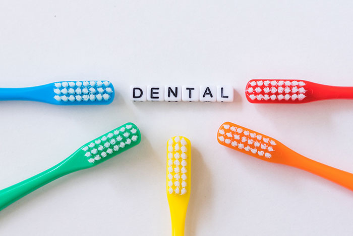 色とりどりの歯ブラシがDENTALの文字を囲む写真